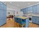 Open kitchen with light blue cabinets, hardwood floors, a kitchen island, and stainless steel appliances at 3308 Churchill Rd, Raleigh, NC 27607