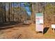 A park entrance sign with information along a tree-lined path under a bright sky at 3308 Churchill Rd, Raleigh, NC 27607