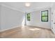 Light-filled bedroom with hardwood floors, white walls, and two windows offering views of the outside at 3832 Noremac Dr, Raleigh, NC 27612