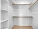 A walk-in closet with hardwood floors, white walls, wooden rails and storage shelves at 3832 Noremac Dr, Raleigh, NC 27612