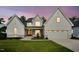 Inviting two-story home with a white exterior, stone details, and a professionally landscaped front yard at 3832 Noremac Dr, Raleigh, NC 27612