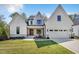 Beautiful white modern farmhouse with stone accents and a well-manicured front lawn at 3832 Noremac Dr, Raleigh, NC 27612