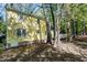 Side view of yellow house with white trim, windows, and deck, nestled amongst mature trees at 3900 Inkberry Ct, Apex, NC 27539