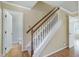 Interior staircase featuring carpeted steps, wooden railing and trim, with an open door to a half-bath at 3900 Inkberry Ct, Apex, NC 27539