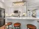 Bright kitchen features white cabinets, quartz countertops, and a large center island with stool seating at 3900 Maplefield Dr, Raleigh, NC 27613