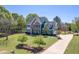 Expansive view of a brick and siding home, mature trees, driveway, and large grassy yard at 3905 Autumn Creek Dr, Fuquay Varina, NC 27526