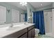 A bathroom featuring a double sink vanity and shower/tub combo with a blue curtain at 4523 Tarkiln Pl, Wake Forest, NC 27587
