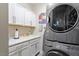Well-lit laundry room with white cabinets, sink, and stacked washer and dryer at 463 Old Piedmont Cir, Chapel Hill, NC 27516