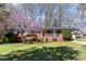 Charming brick home featuring a cozy front porch and a lovely flowering tree in the front yard at 5033 Green Oak Dr, Durham, NC 27712