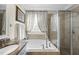 Bright bathroom featuring soaking tub, glass enclosed shower, and natural tile work throughout at 504 Skygrove Dr, Holly Springs, NC 27540