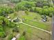Expansive aerial view of a country estate featuring lush greenery, a pond, multiple structures, and long driveway at 5069 Cokesbury Rd, Fuquay Varina, NC 27526