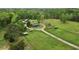 Scenic aerial view of a rural homestead featuring green pasture, barns, and a tree-lined perimeter fence at 5069 Cokesbury Rd, Fuquay Varina, NC 27526