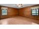 Bedroom with wood paneling, ceiling fan, and two windows with peaceful outdoor views at 5069 Cokesbury Rd, Fuquay Varina, NC 27526