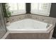 A serene bathroom features a corner soaking tub with jets and tile surround, nestled under a window at 515 Bexley Bluff Ln, Cary, NC 27513
