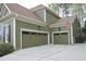 Three-car garage featuring traditional doors, decorative lamps, and pristine driveway at 515 Bexley Bluff Ln, Cary, NC 27513