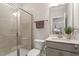 This bathroom features a glass shower, gray vanity, sink, and toilet, with a neutral color palette and a large mirror at 5209 Woodlawn Dr, Durham, NC 27703