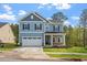 Charming two-story home with blue siding, a covered porch, and a two-car garage in a lush landscape at 5209 Woodlawn Dr, Durham, NC 27703
