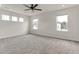 A spacious empty carpeted bedroom with a ceiling fan is illuminated by natural light streaming through multiple windows at 5712 Agrinio Way, Raleigh, NC 27603