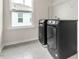 Tile laundry room featuring black washer and dryer, and window at 5712 Agrinio Way, Raleigh, NC 27603