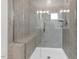 A modern shower features gray tiled walls, a glass door, built-in seating, and ample lighting at 5712 Agrinio Way, Raleigh, NC 27603