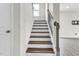 A brightly lit staircase features dark wood steps and sleek metal railing, leading to the upper level of the home at 5712 Agrinio Way, Raleigh, NC 27603