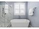 This bathroom offers a soaking tub and walk-in shower with modern, neutral tones and window with shutters at 7825 Green Hope School Rd, Cary, NC 27519