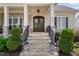 Charming home entrance featuring stone steps, wrought iron railings, and decorative flower urns at 7825 Green Hope School Rd, Cary, NC 27519