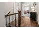 Hallway with hardwood floors, wood railing, and view of living room with comfortable couch at 7825 Green Hope School Rd, Cary, NC 27519