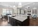 Open concept kitchen with a large island, dark cabinetry and view into living and dining area at 7825 Green Hope School Rd, Cary, NC 27519