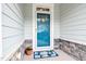 Close-up of a vibrant blue front door with stone accents and a welcoming floral doormat at 85 Bramble Ln, Clayton, NC 27527