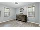 Bright bedroom with two windows, wood-look flooring, and a dresser with modern butterfly art at 1105 Terrace Ct, Raleigh, NC 27615