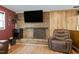 Cozy living room features a brick fireplace, wood-paneled wall, and comfortable leather furniture at 1105 Terrace Ct, Raleigh, NC 27615