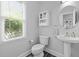 Bright half bathroom featuring a pedestal sink, toilet, and window with natural light at 119 Weaver Mine Trl, Chapel Hill, NC 27517