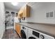 Laundry room with natural wood cabinets, long countertops, washer, and dryer at 119 Weaver Mine Trl, Chapel Hill, NC 27517