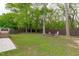 Expansive backyard with mature trees, a firepit area, and fence offers a serene outdoor space for relaxation and activities at 120 Cabrita Ct, Holly Springs, NC 27540