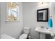 Bright half bath features a pedestal sink, framed mirror, toilet and a window at 1211 Yellow Wood Dr, Mebane, NC 27302