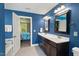 Blue bathroom featuring a double sink vanity, ceramic tile flooring, and doorway leading to bedroom at 1211 Yellow Wood Dr, Mebane, NC 27302
