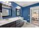 Bright blue bathroom featuring a double sink vanity and doorway that leads to a closet with built-in shelving at 1211 Yellow Wood Dr, Mebane, NC 27302