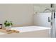 Close up of a soaking tub with modern faucet, plant and wood decor at 1213 Rocky Point Ln, Durham, NC 27712