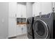 Bright laundry room features modern washer and dryer, sink and white shaker cabinets at 1213 Rocky Point Ln, Durham, NC 27712