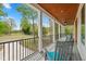 Covered porch with views of trees and a golf course, featuring gray chairs and teal cushions at 1213 Rocky Point Ln, Durham, NC 27712