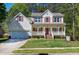 Charming two-story home with a covered front porch, red shutters, and a well-manicured lawn at 1310 Country Club Dr, Durham, NC 27712