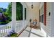 Inviting front porch featuring a rocking chair, side table, and decorative potted plants at 1310 Country Club Dr, Durham, NC 27712