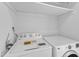 Bright laundry room with white washer and dryer, featuring overhead shelving for storage at 1323 Fairmont St, Durham, NC 27713