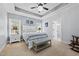 Light-filled bedroom with a tray ceiling, a ceiling fan and light fixture, and decor above the bed at 1325 George Bason Rd, Graham, NC 27253