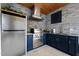 Outdoor kitchen with stainless steel appliances, blue cabinets, and tiled backsplash at 1325 George Bason Rd, Graham, NC 27253