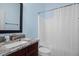 This bathroom features dark wood cabinets with a granite top and a shower/tub combo with a white curtain at 1422 Gormly Cir, Sanford, NC 27330
