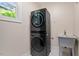 This laundry room features a stacked washer and dryer, and a utility sink by a window at 1422 Gormly Cir, Sanford, NC 27330