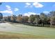 A scenic view of a golf course and pond nestled among mature trees and landscaping at 1537 Heritage Club Ave, Wake Forest, NC 27587