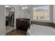 Bright bathroom featuring a soaking tub, a dark vanity with modern fixtures, and a walk-in closet at 1840 Flint Valley Ln, Apex, NC 27502